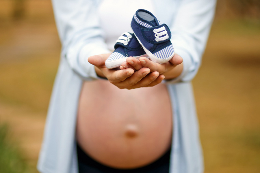 Femme enceinte avec chaussons de nourisson